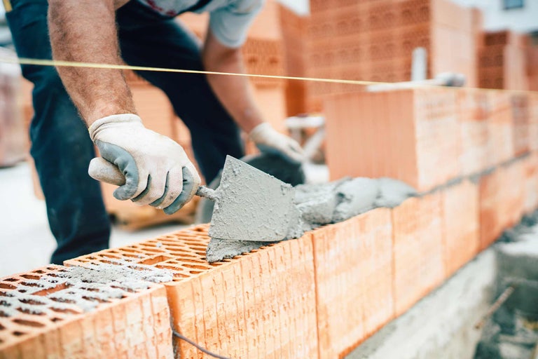 Maurer beim Bau einer Ziegelmauer mit Mörtel und Kelle