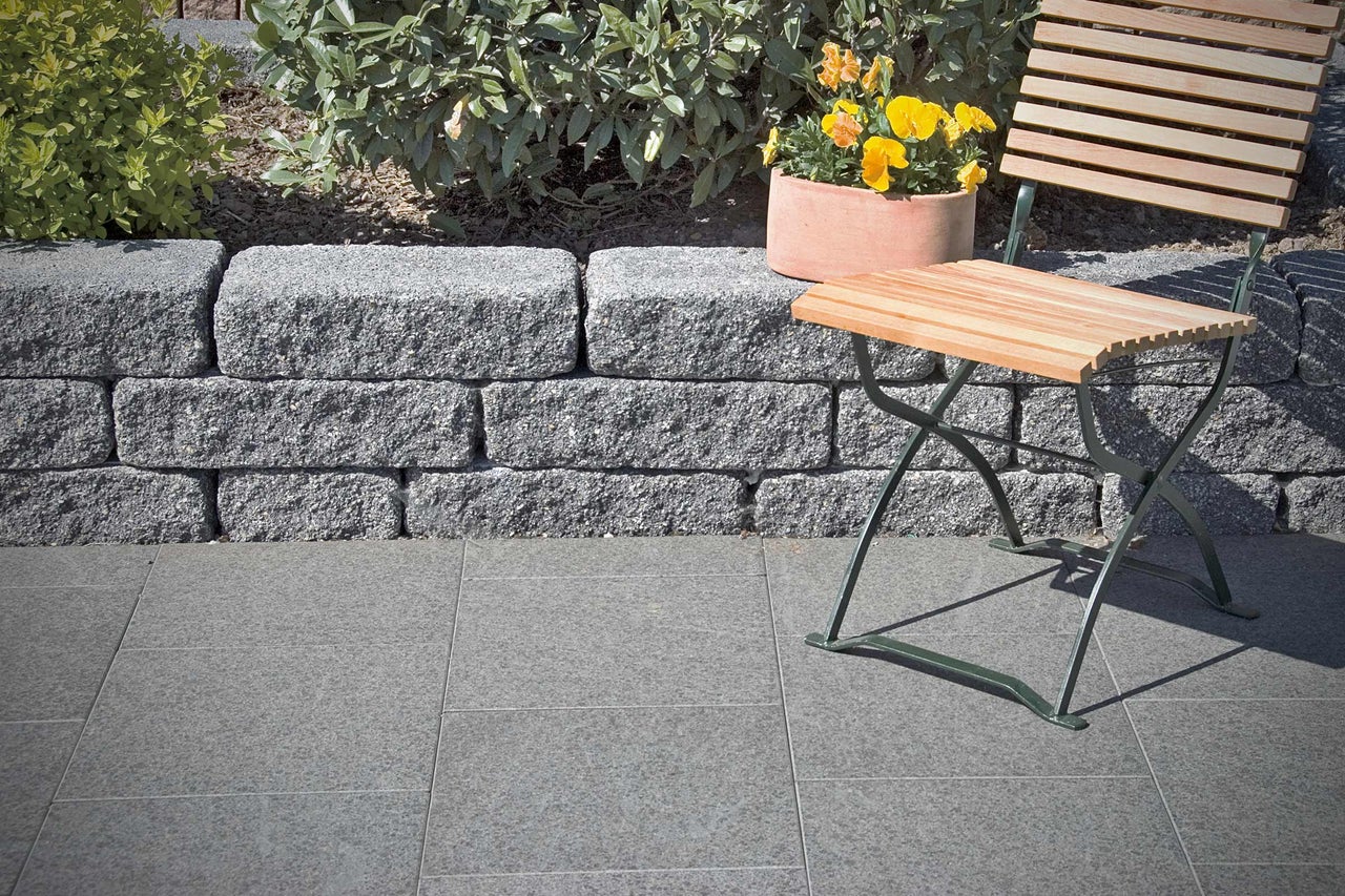Aménagement de jardin avec mur de pierres sèches, pavés, fleurs et mobilier de jardin