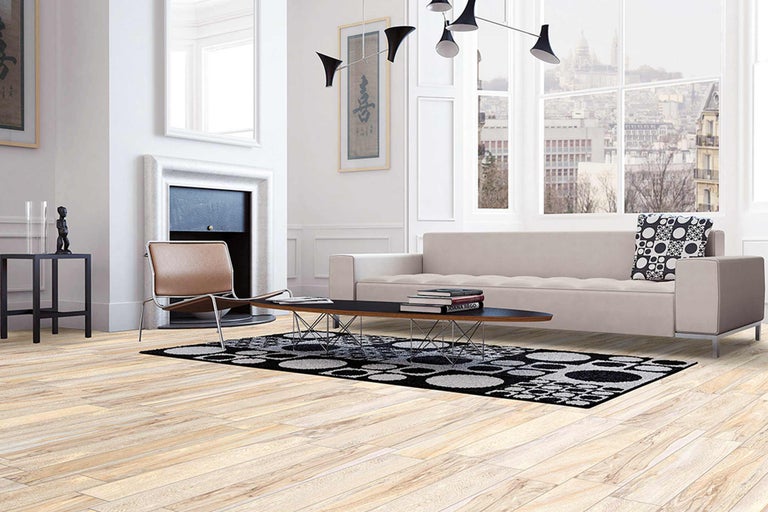 Heller Wohnraum mit Sofa, Sessel, Teppich und Holzboden