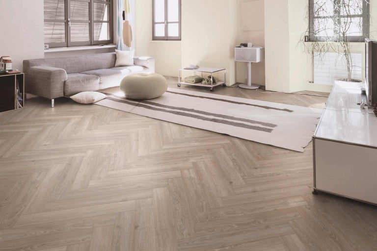 Salon avec parquet à chevrons, canapé et tapis