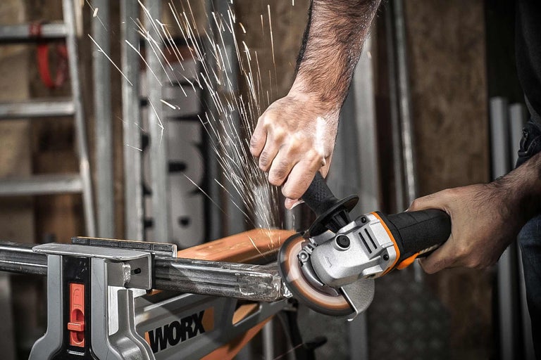 Eine Person verwendet einen Winkelschleifer mit Funkenflug, um ein Metallstück zu bearbeiten, das in einem Schraubstock eingespannt ist.