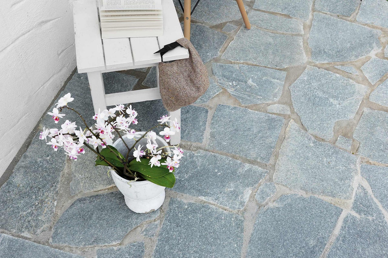 Terrasse avec dalles en pierre naturelle, décorée avec table, livres, sac et plante en pot