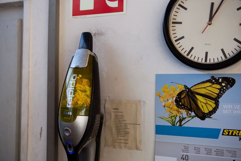 Akkusauger von AEG, Wanduhr, Telefonliste und Kalender hängen an der Wand