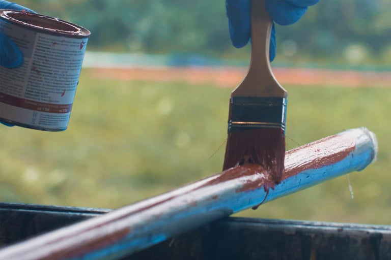De la peinture est appliquée sur un tube avec un pinceau.