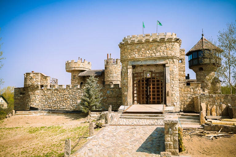 Außenansicht eines Schlosses mit Steinmauern und Türmen unter blauem Himmel