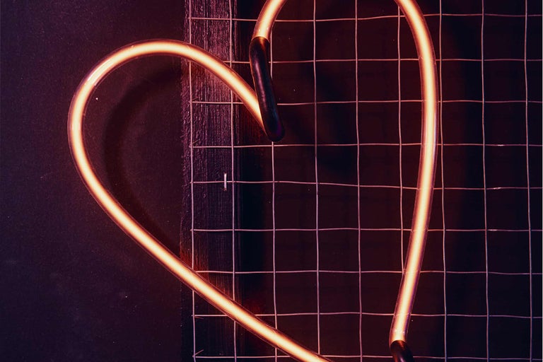 Neonherz auf einem Metallgitter