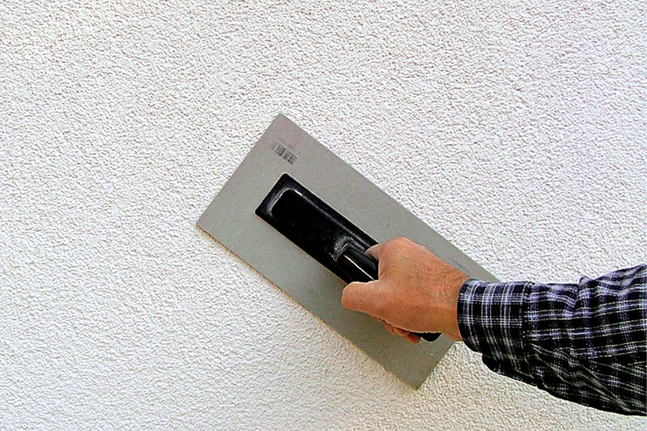 Mur extérieur avec structure d'enduit et artisan avec taloche