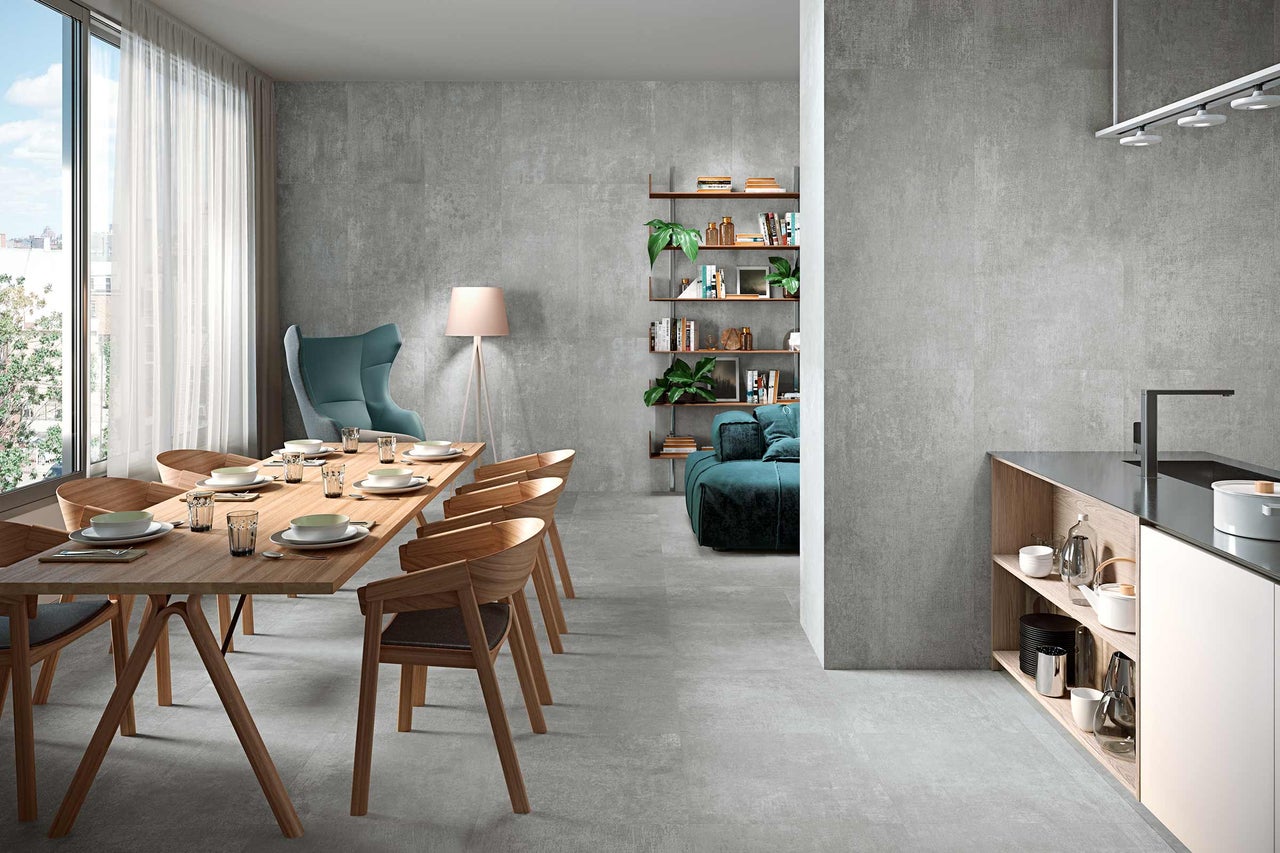Intérieur avec table à manger, chaises, étagères et sol en grès cérame gris.