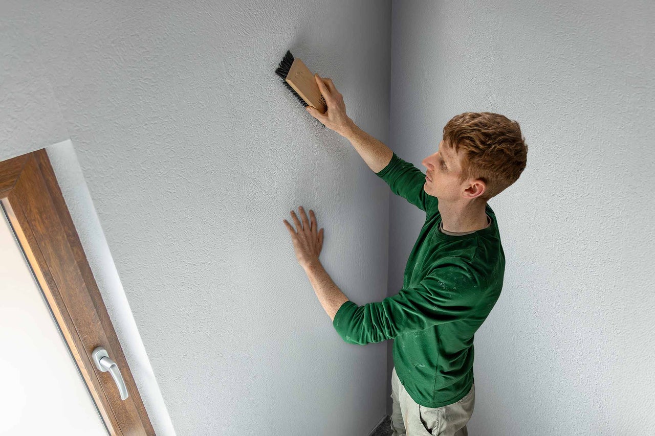 Un homme structure un mur avec une brosse