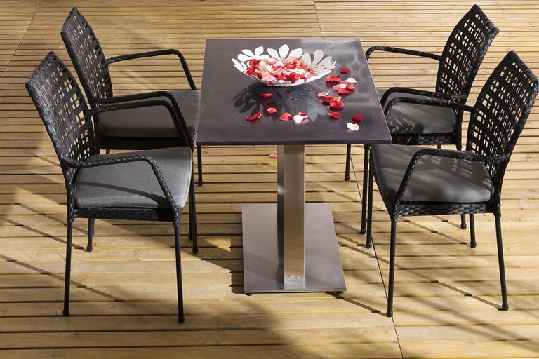 Ensemble de table de jardin avec quatre fauteuils en rotin et une table avec un bol de pétales de fleurs
