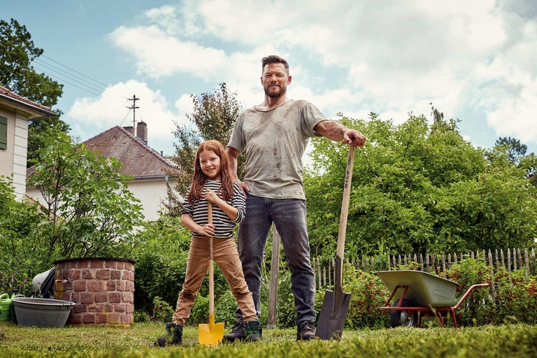 Père et fille dans le jardin avec bêche et brouette