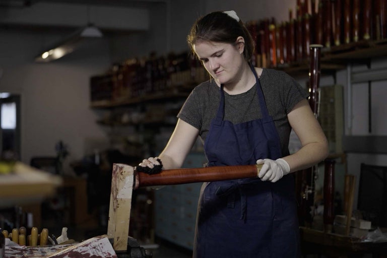 Frau bearbeitet Holzstab in Werkstatt