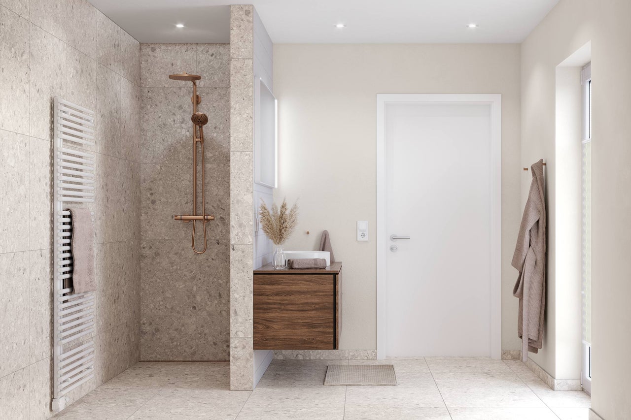 Salle de bains moderne avec douche à l'italienne, carrelage en terrazzo, robinetterie en cuivre et meuble sous-lavabo en bois.
