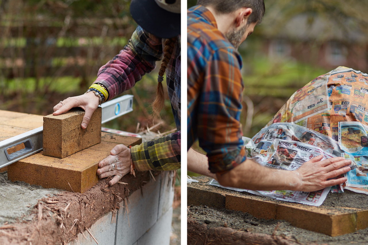 Zwei Personen arbeiten mit Ziegelsteinen und einer Wasserwaage im Freien, um eine Struktur zu bauen.