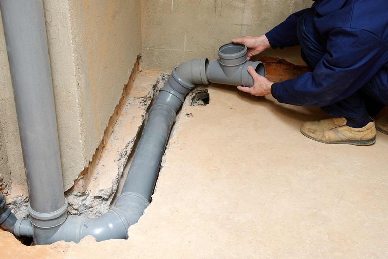 Installation de tuyaux d'évacuation gris dans la cave par un plombier