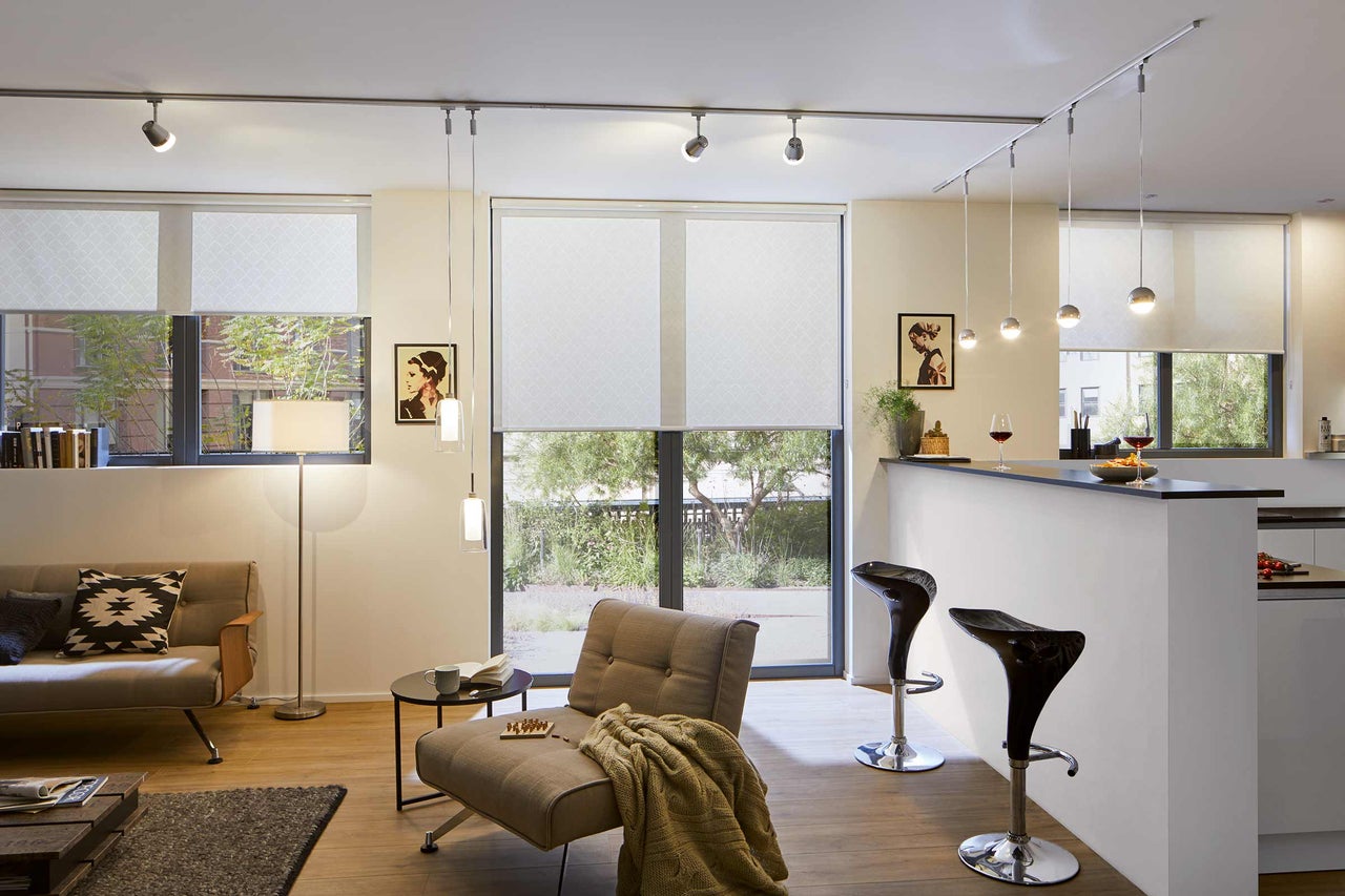 Salon avec canapé, fauteuil, bar, plafonnier et stores enrouleurs