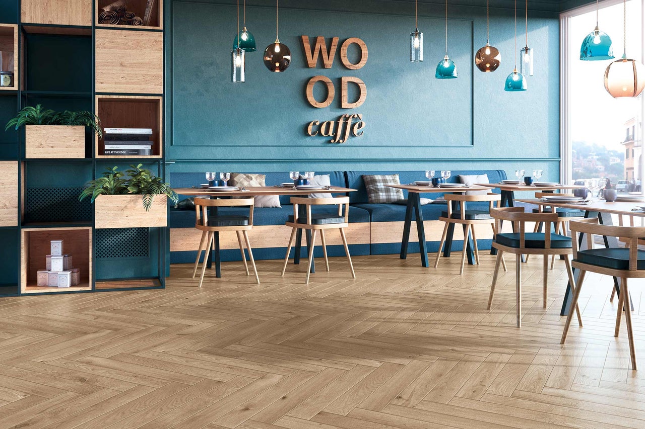 Photo intérieure d'un café avec des tables, des chaises et un parquet en motif de chevrons.