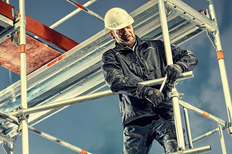 Un homme portant un casque de protection monte un échafaudage.