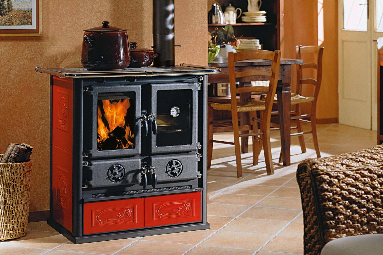 Poêle à bois avec fonction de cuisson, panier à bois et casseroles dans une salle à manger.