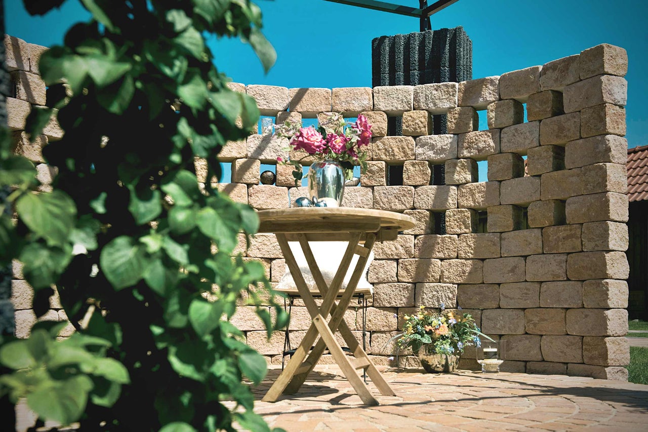 Mur de jardin décoratif en pierre avec table et compositions florales