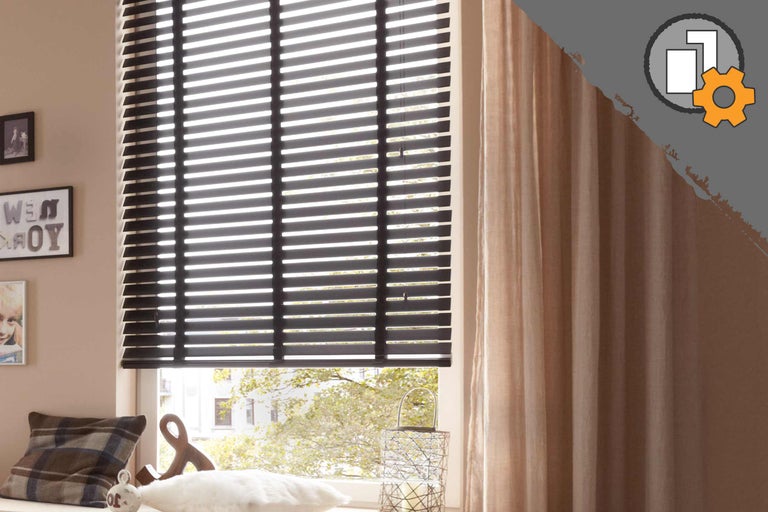 Pièce avec stores vénitiens et rideaux noirs à la fenêtre.