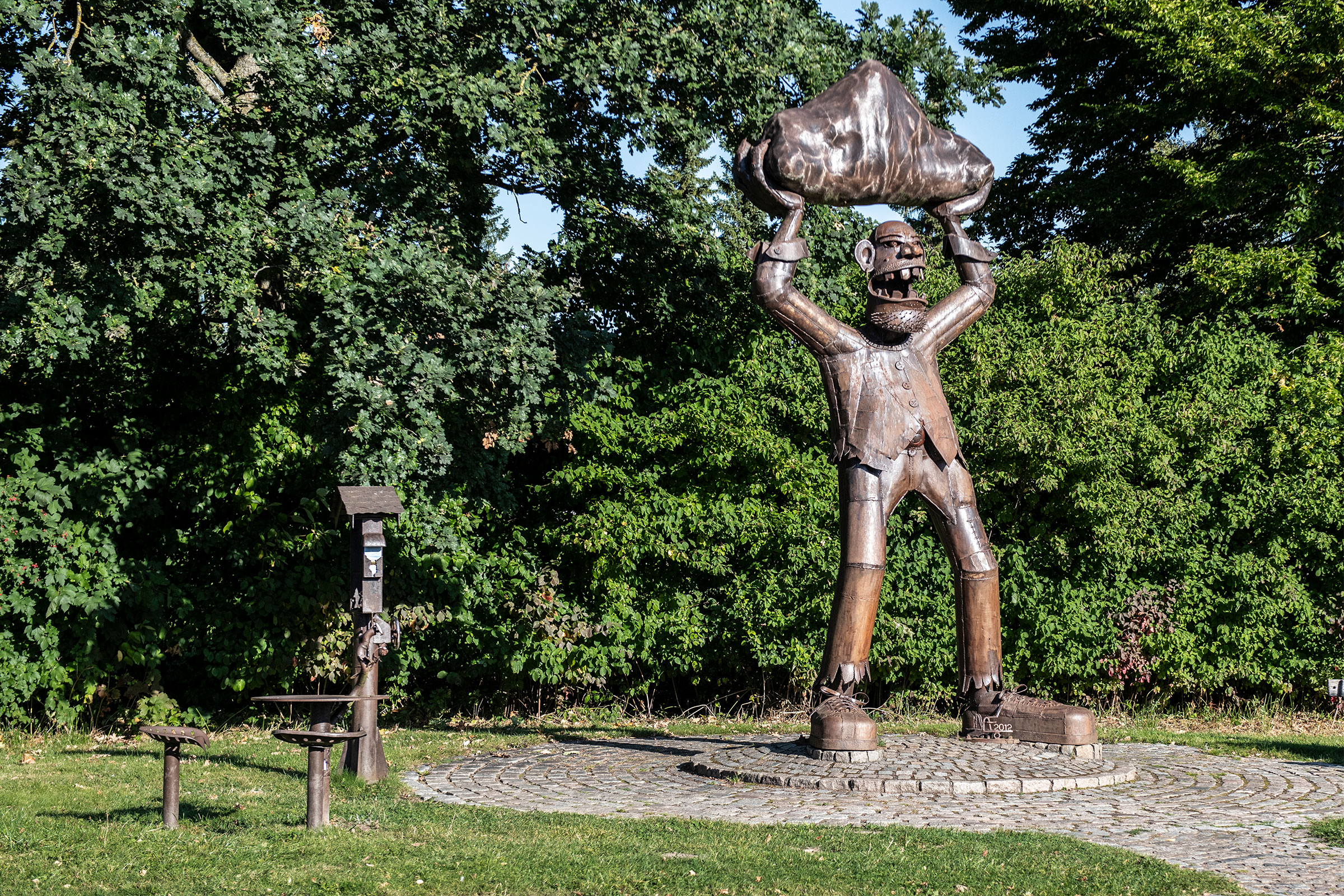 Skulptur einer Figur, die einen Felsen über dem Kopf hält