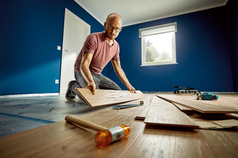 Un homme pose du stratifié dans une pièce avec des outils.