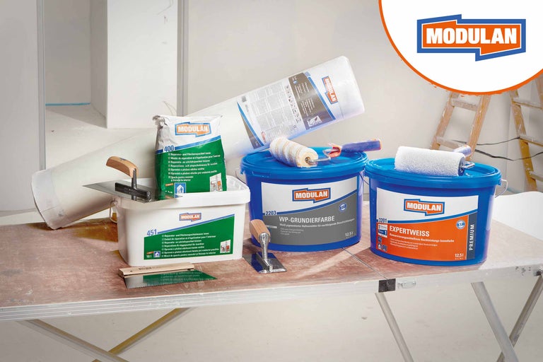 Produktaufstellung mit Modulan Reparaturspachtel, Grundierfarbe, Expertweiss Farbe, Malervlies und Werkzeugen