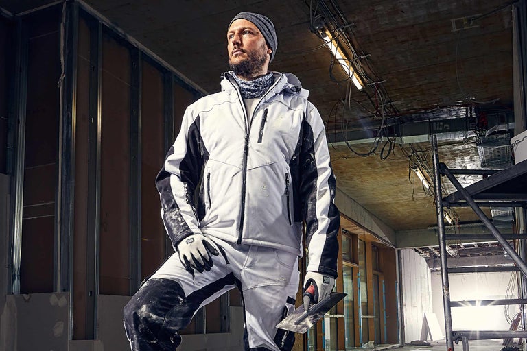 Artisan en vêtements de travail avec une truelle sur un chantier.