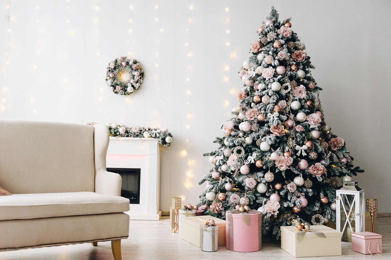 Sapin de Noël décoré dans un salon avec fauteuil, cheminée et cadeaux.