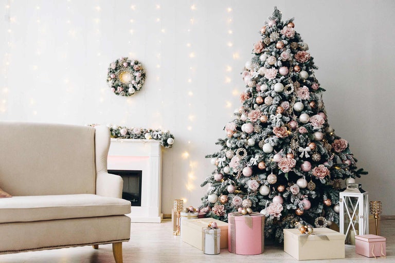 Sapin de Noël décoré dans un salon avec fauteuil, cheminée et cadeaux.