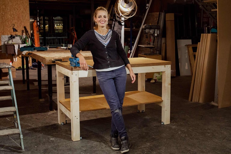 Femme appuyée sur un établi en bois avec un étau