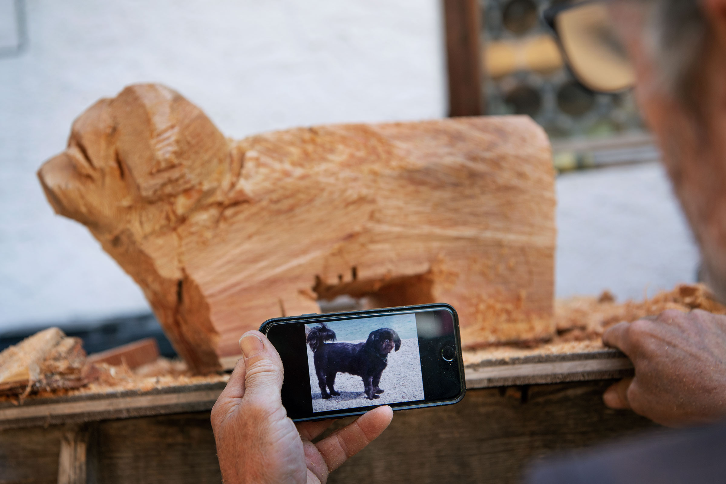 Holzrohling eines Hundes und ein Mobiltelefon mit einem Foto von einem Hund