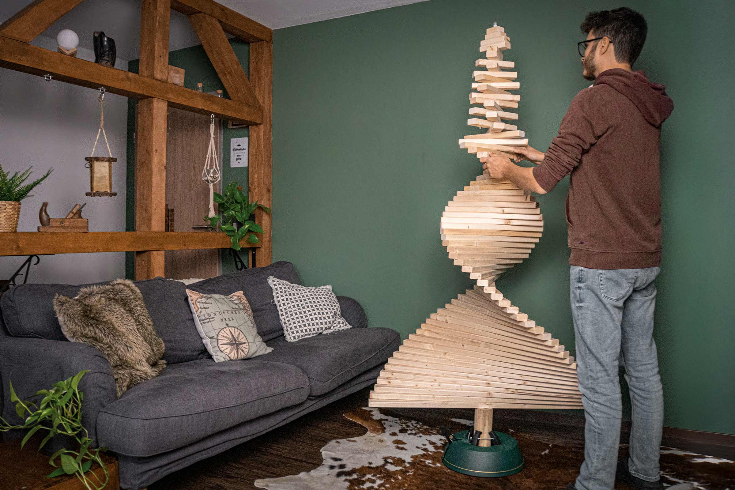 Un homme construit un sapin de Noël design en bois dans le salon.