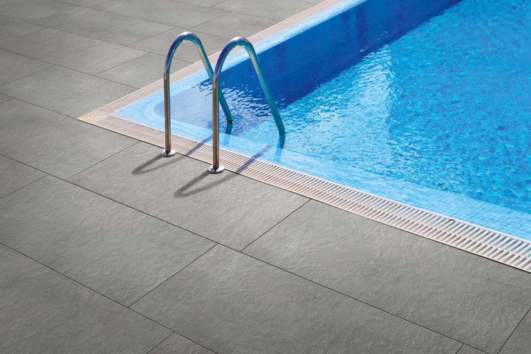 Dalles de terrasse grises à côté d'une piscine avec échelle.