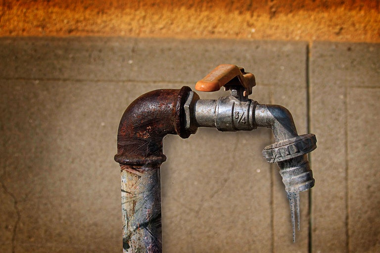 Ein Wasserhahn aus Metall mit Rost und Eiszapfen