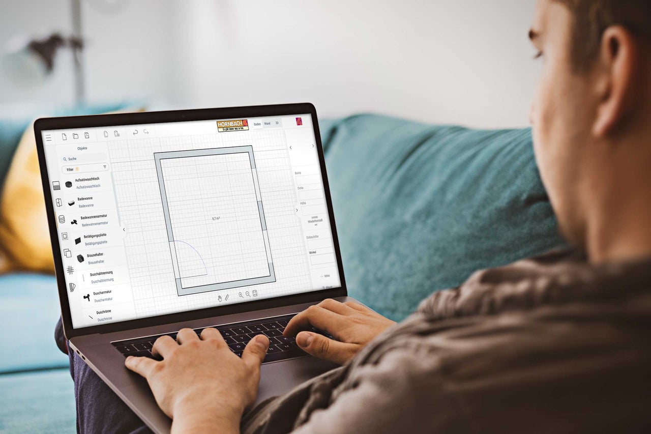 Un homme utilise un ordinateur portable avec le logiciel de planification de salle de bains Hornbach pour la planification de salle de bains.