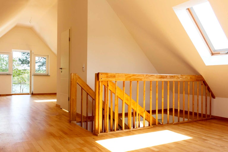 Grenier lumineux avec escalier en bois, fenêtre de toit et parquet