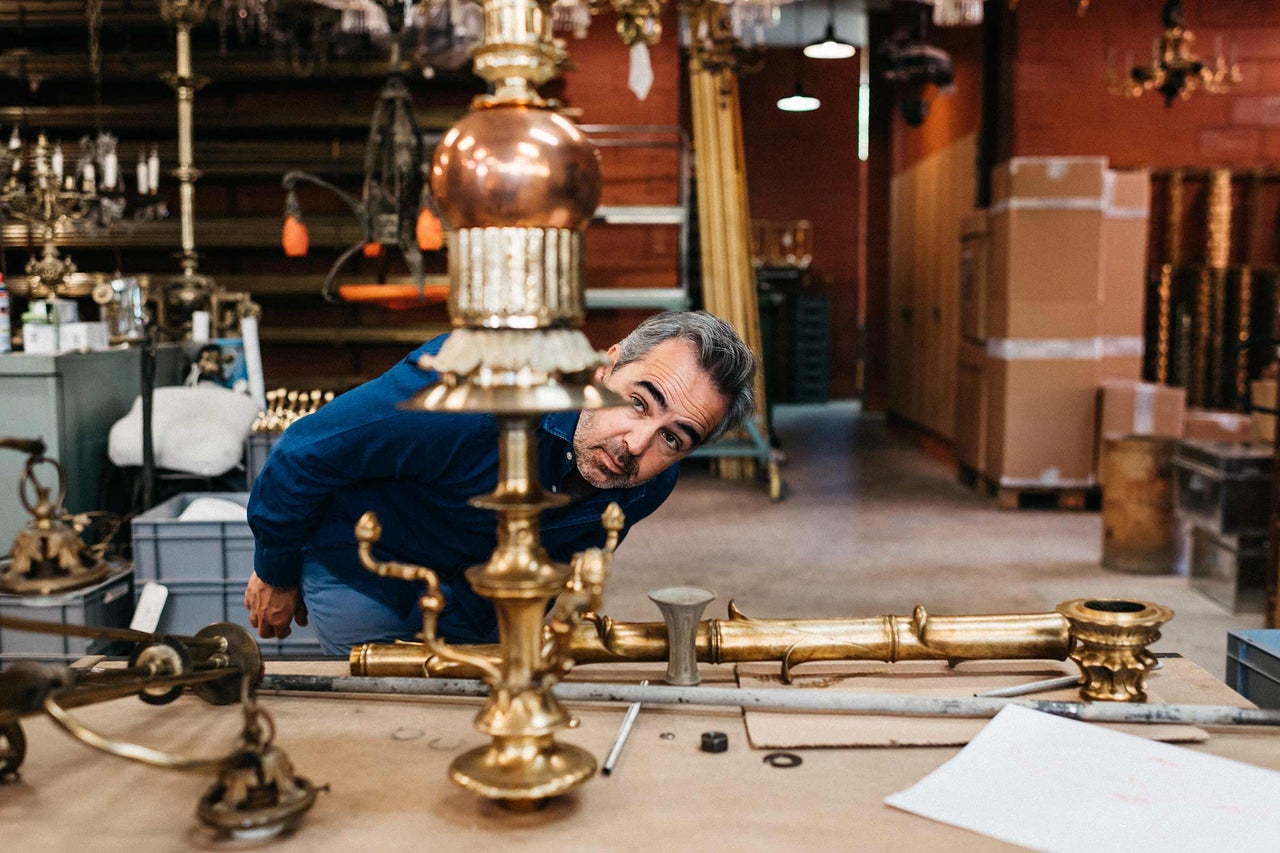 Homme regardant des éléments de lustre dorés dans un atelier