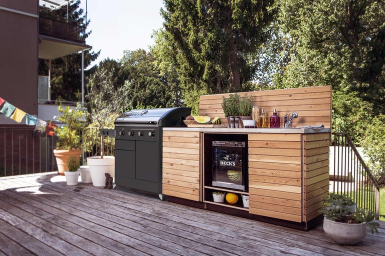 Cuisine extérieure avec barbecue, évier et réfrigérateur sur une terrasse en bois