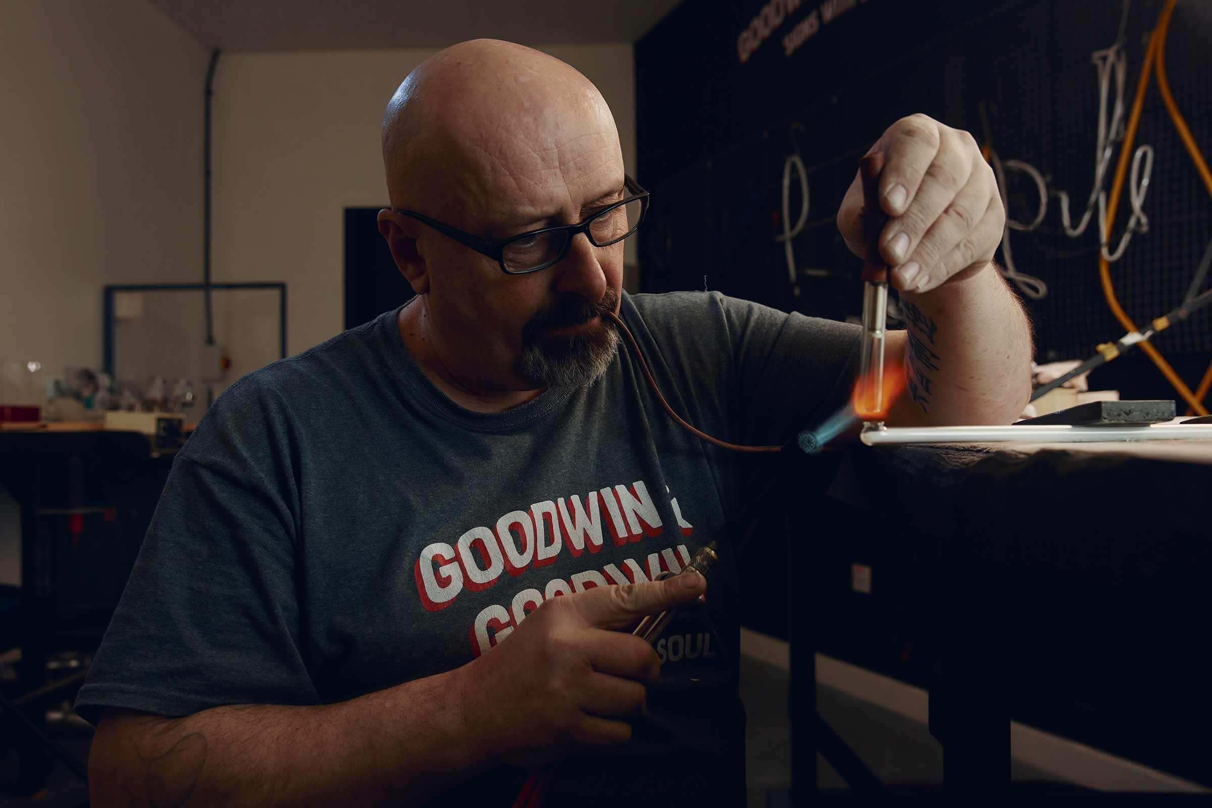 Ein Mann biegt ein Neonrohr mit einer Flamme, um eine Leuchtreklame herzustellen.