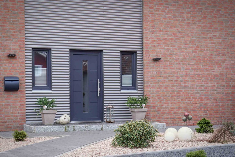 Fassade eines Hauses mit Haustür, Fenstern, Briefkasten und Aussenbeleuchtung