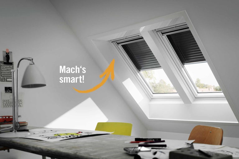 Zwei Dachfenster mit Verdunkelungsrollos in einem hellen Arbeitszimmer