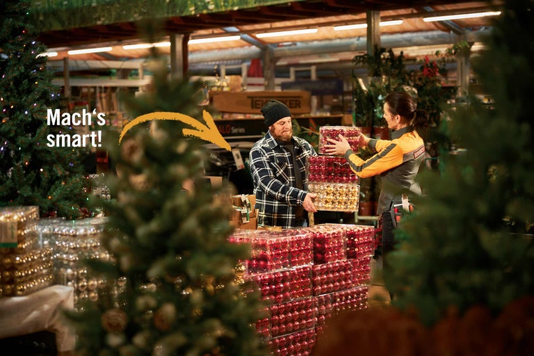 Ein Mann nimmt Weihnachtskugeln von einer Hornbach Mitarbeiterin entgegen.