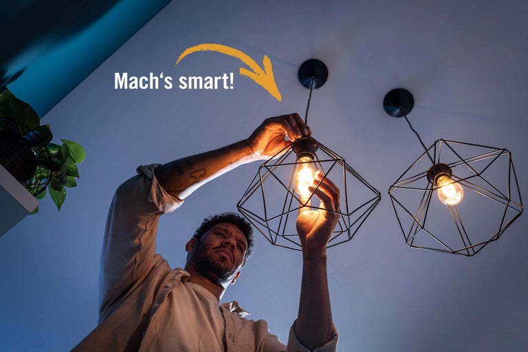 Mann wechselt eine Glühbirne in einer geometrischen Pendelleuchte