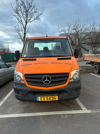Orangefarbener Lieferwagen mit der Aufschrift Bricolage Decoration Materiaux Jardin geparkt