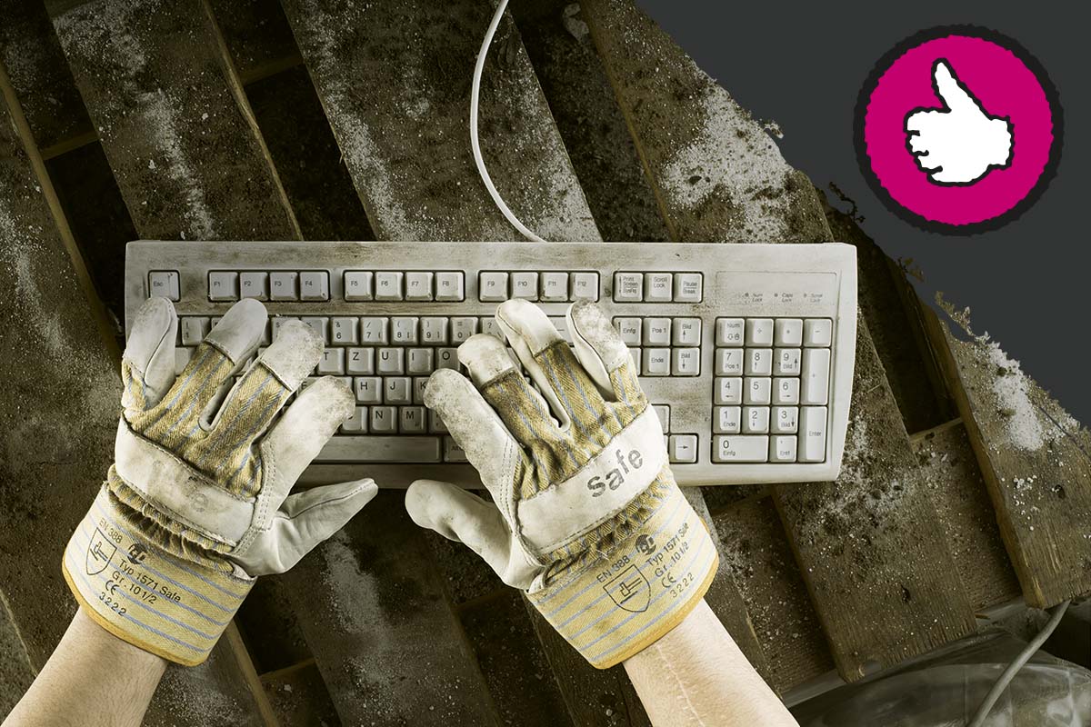 Un clavier d'ordinateur sale est utilisé avec des gants de travail