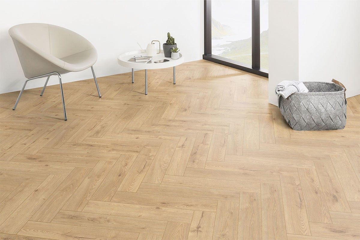 Pièce claire avec parquet à chevrons, fauteuil, table et panier