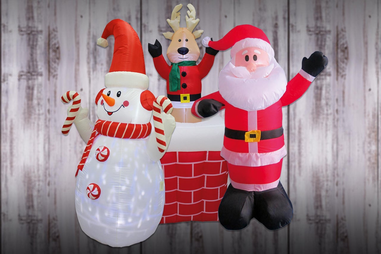 Décoration de Noël gonflable avec bonhomme de neige, renne et Père Noël devant un mur en bois