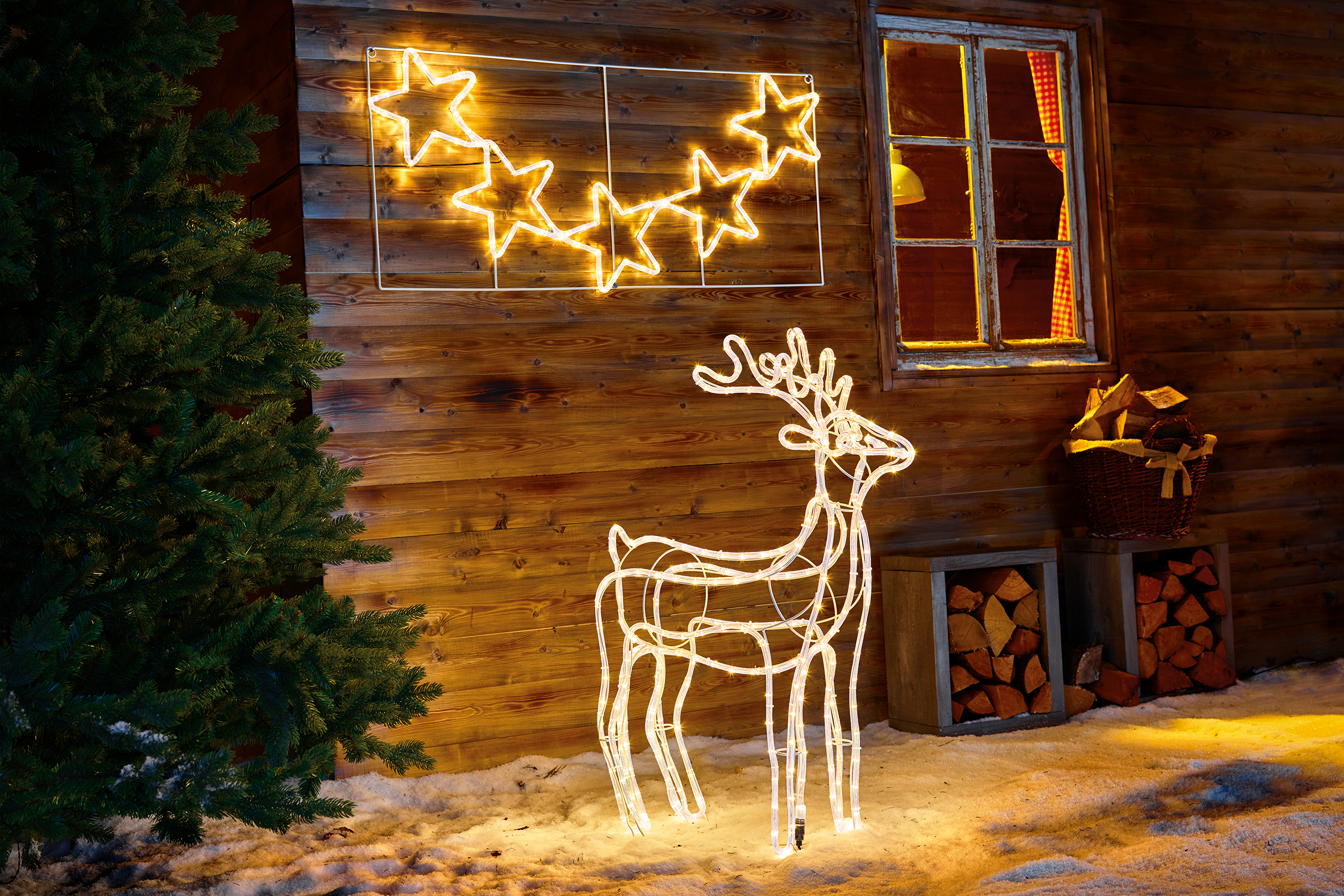 Arrangement décoratif avec motif lumineux en forme d'étoile et de renne devant un mur en bois